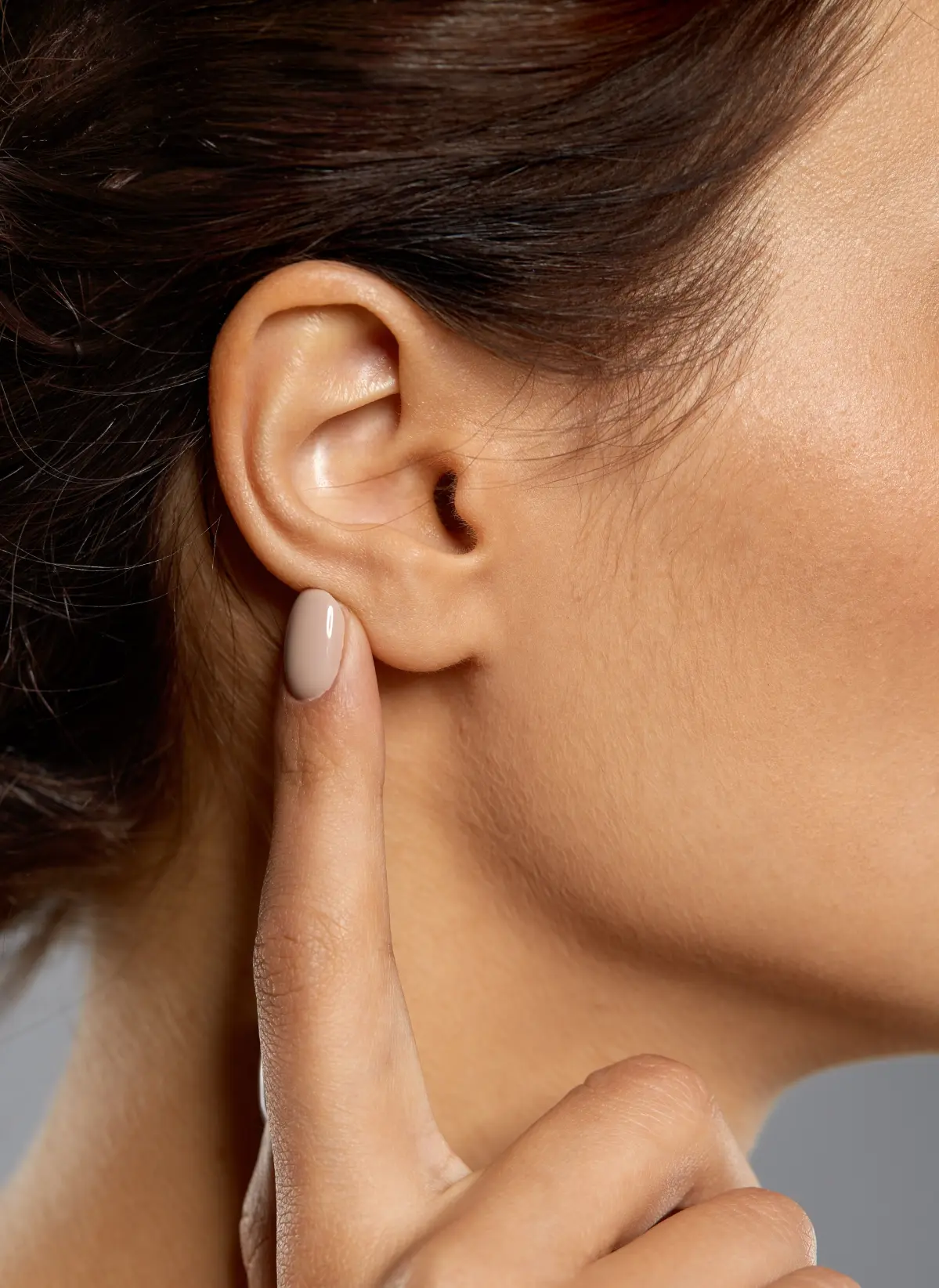 Oreja perfecta tras una otoplastia de la Dra Ruiz Ruiz, de una mujer bella y joven, señalada por su dedo índice.